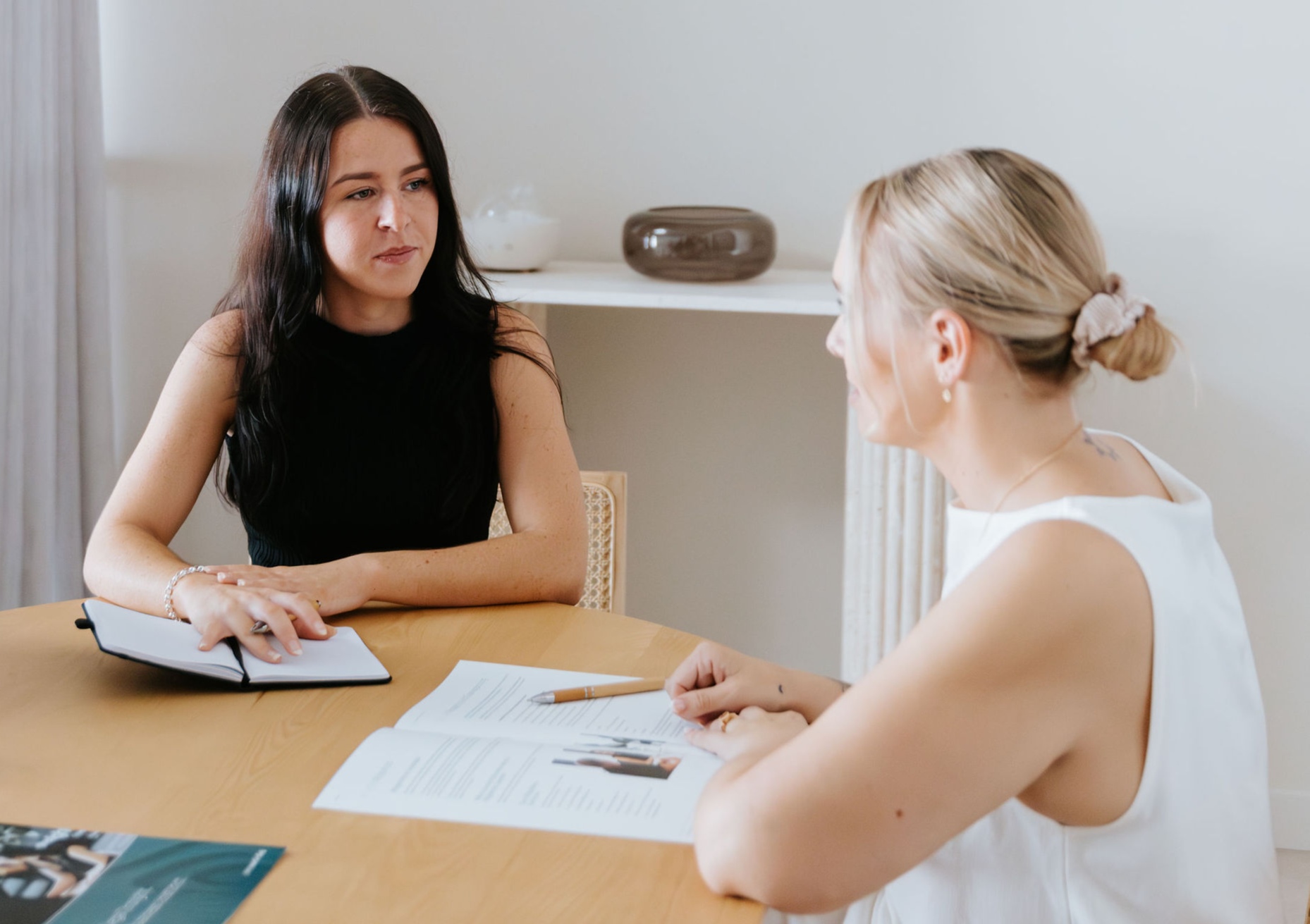 Brunette female lawyer talking to blond female client at board room table