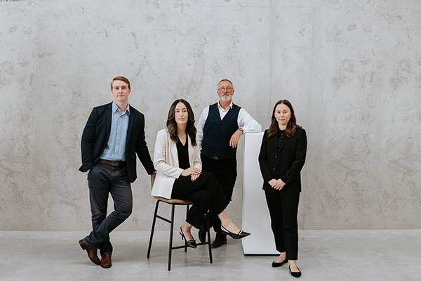 Four solicitors standing in a stone coloured room