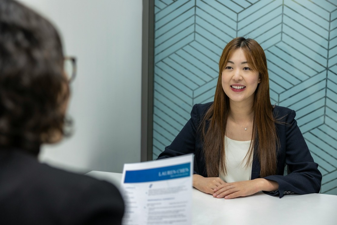 resume-genius-wage-theft-unsplash Long haired smiling female being interviewed for a job