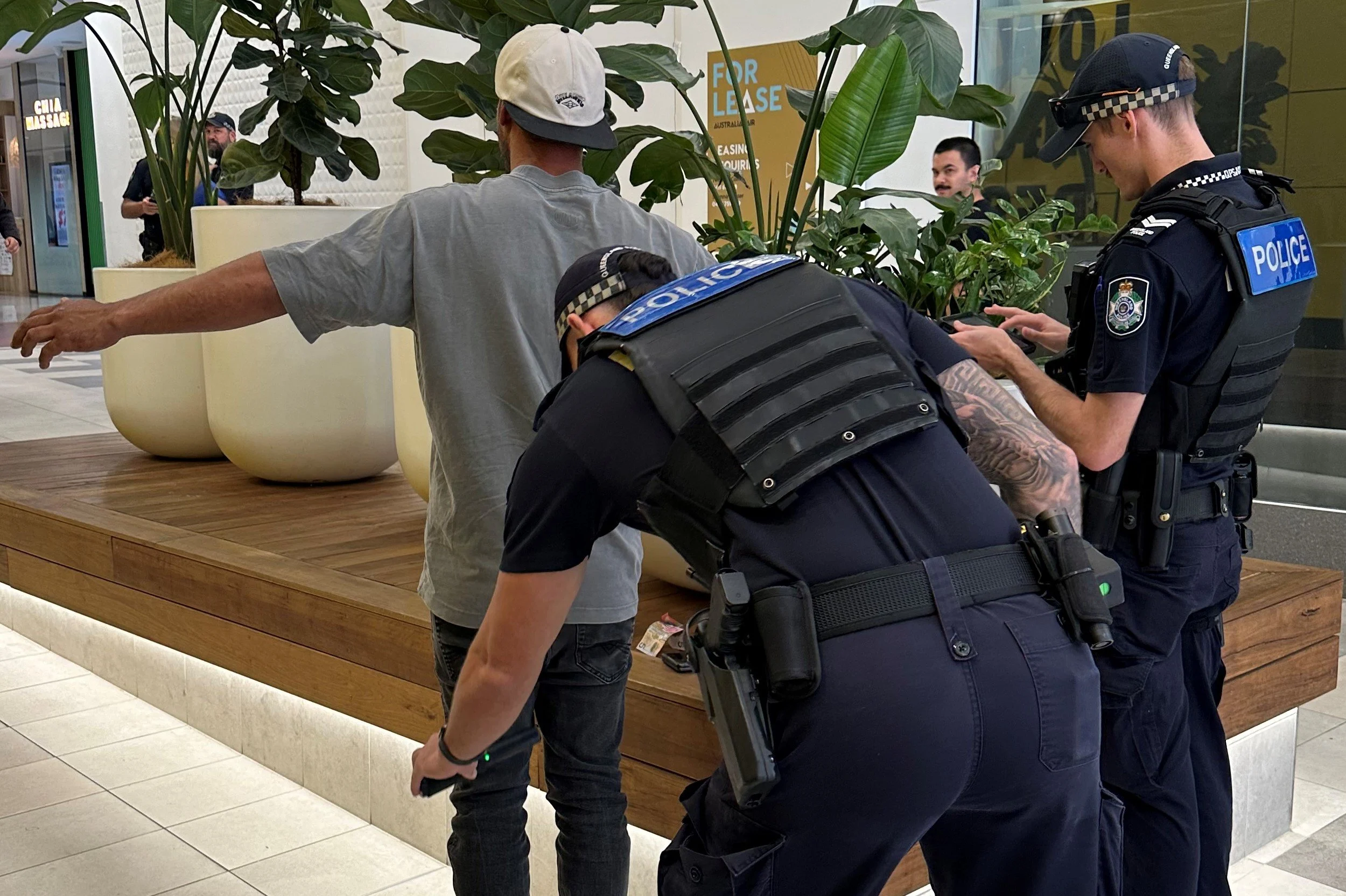Police searching a man at a shopping centre
